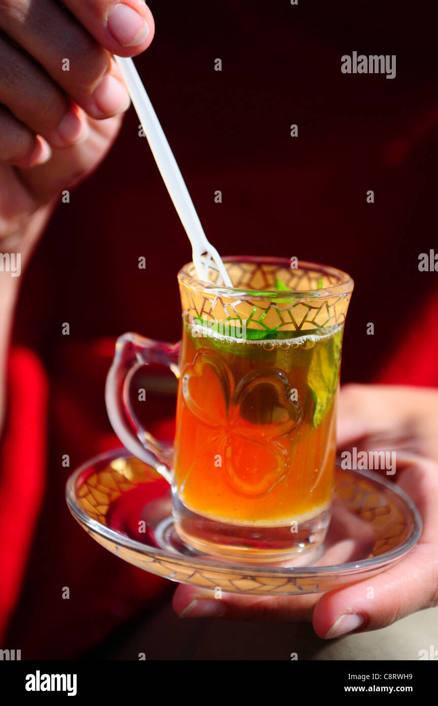 Africa, Tunisia, Tozeur. Tourist having a tea from fresh mint leaves in a beautifully ornamented glass. Stock Photo
