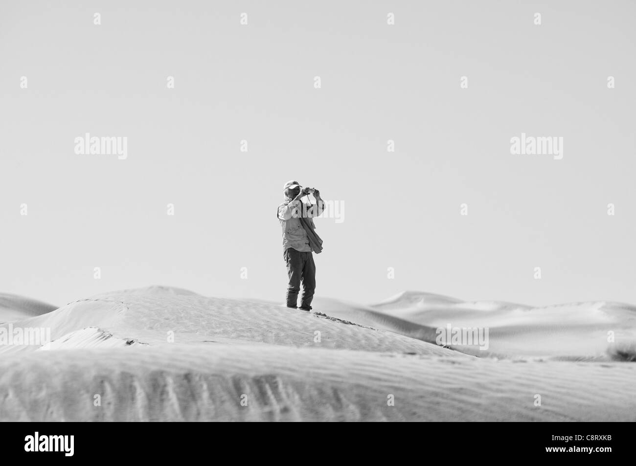 Africa, Tunisia, nr. Tembaine. Desert traveller photographing in the dunes close to Tembaine on the eastern edge of the Grand... Stock Photo