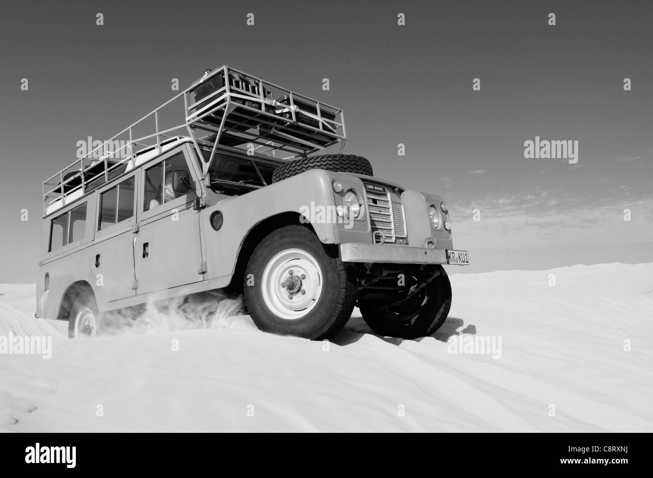 Africa, Tunisia, nr. Tembaine. Desert travellers driving their 1975 Land Rover Series 3 Station Wagon through a sandfield ... Stock Photo