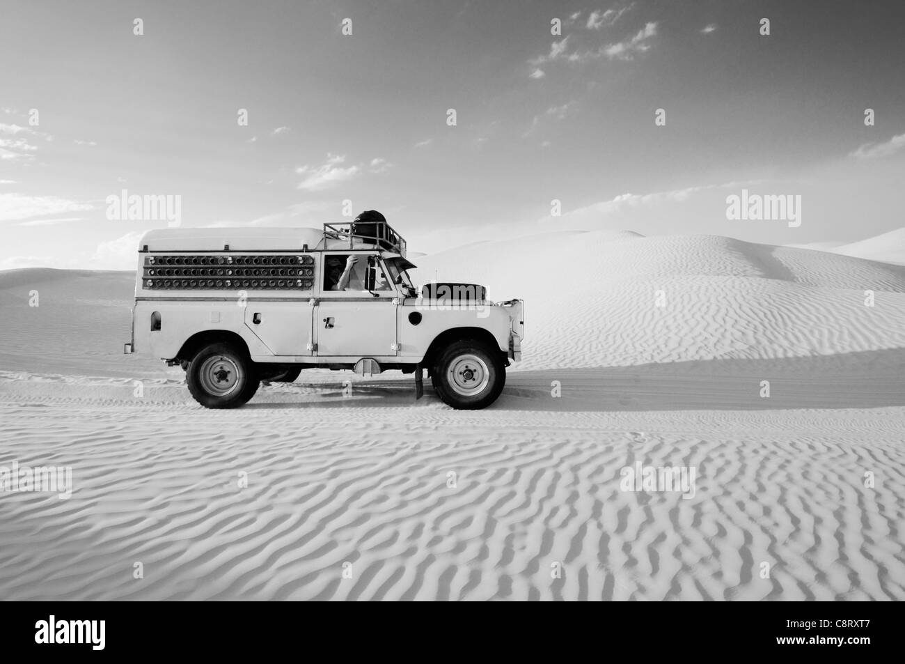 Africa, Tunisia, nr. Ksar Rhilane. Desert travellers driving their 1978 Land Rover Series 3 Dormobile through a sandfield ... Stock Photo