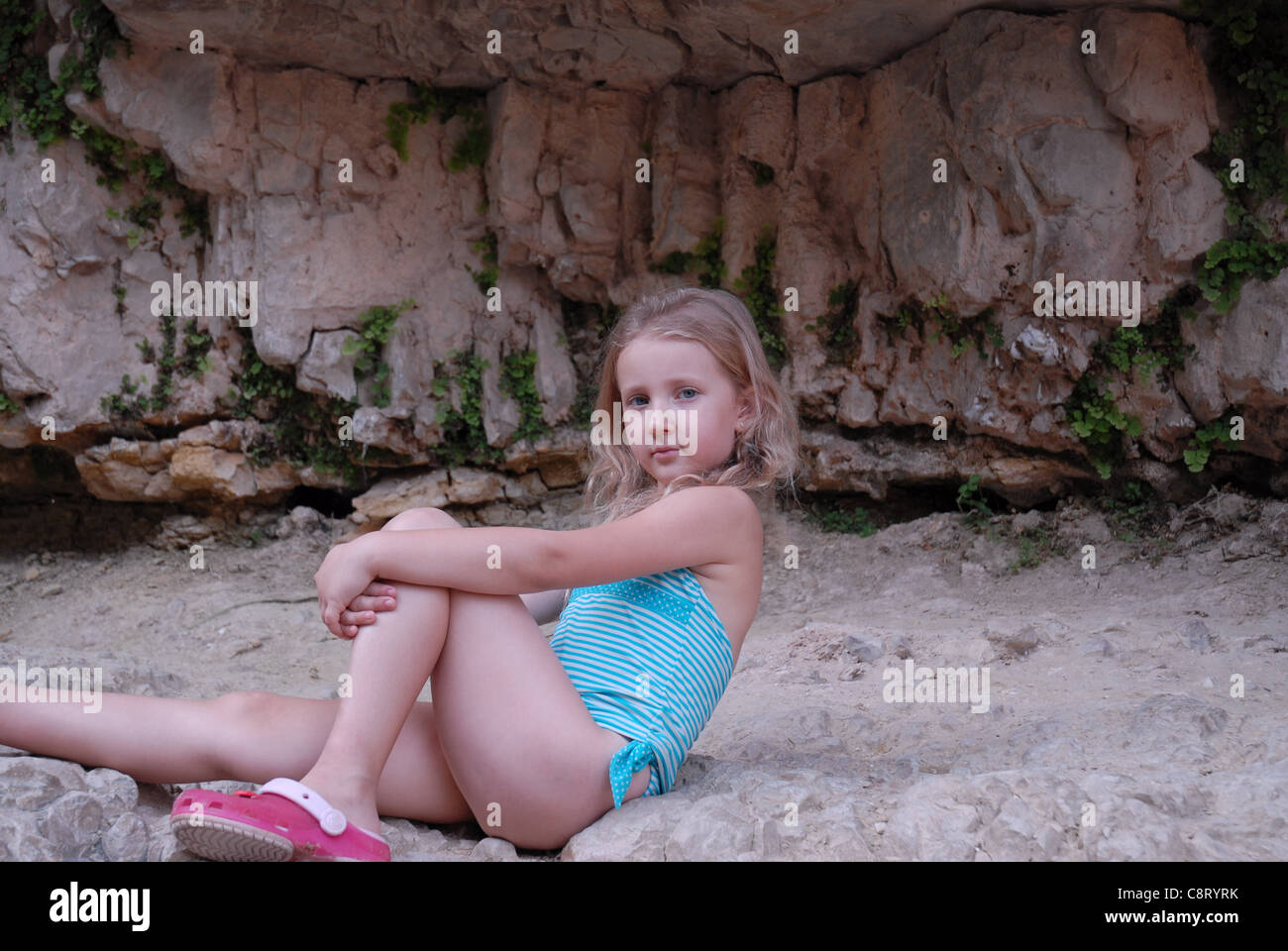 the girl child among the stones on the outside Stock Photo