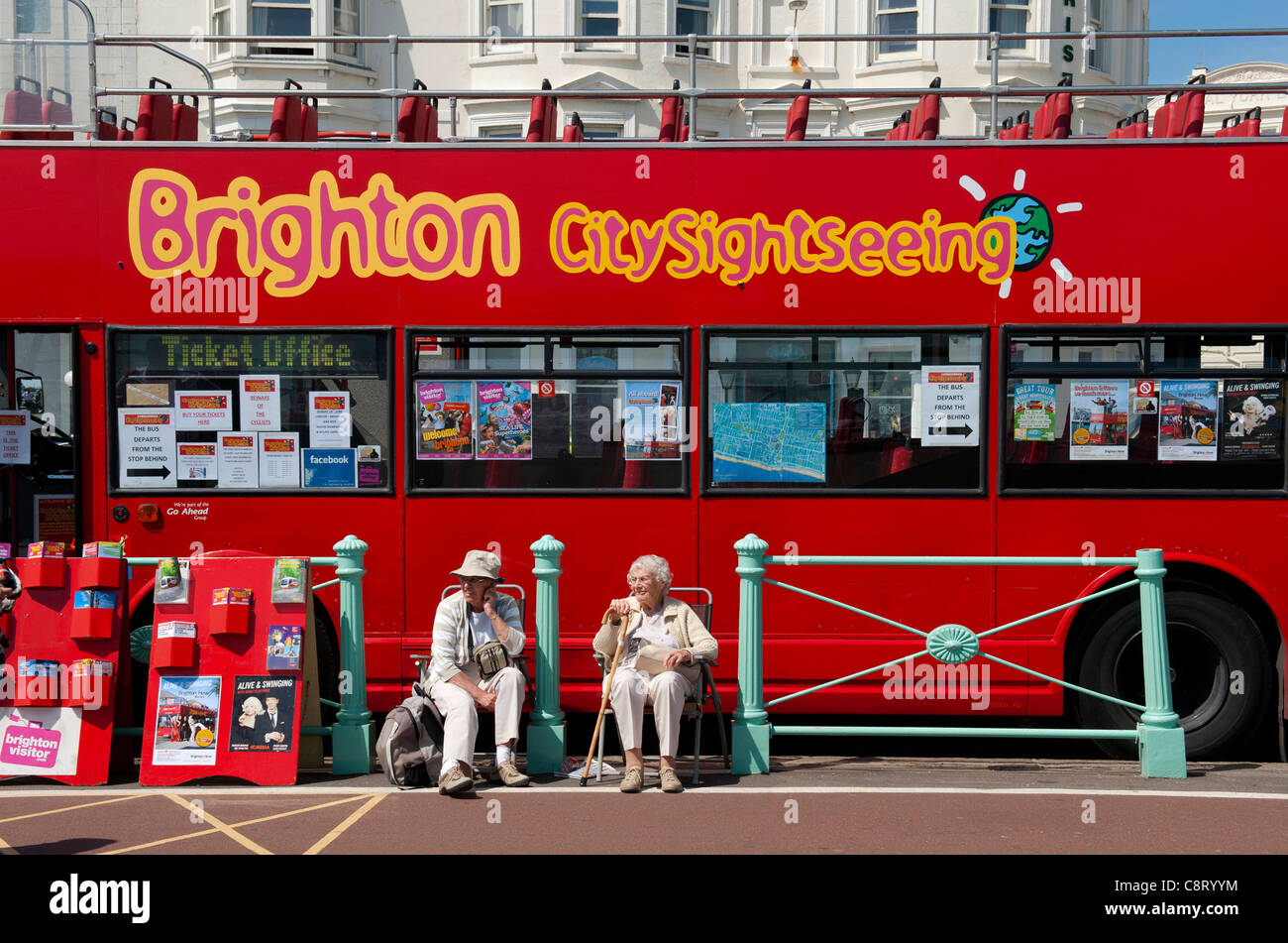 Elderly couple sittong by a tourist bus on the seafront in Brighton, Sussex, UK Stock Photo