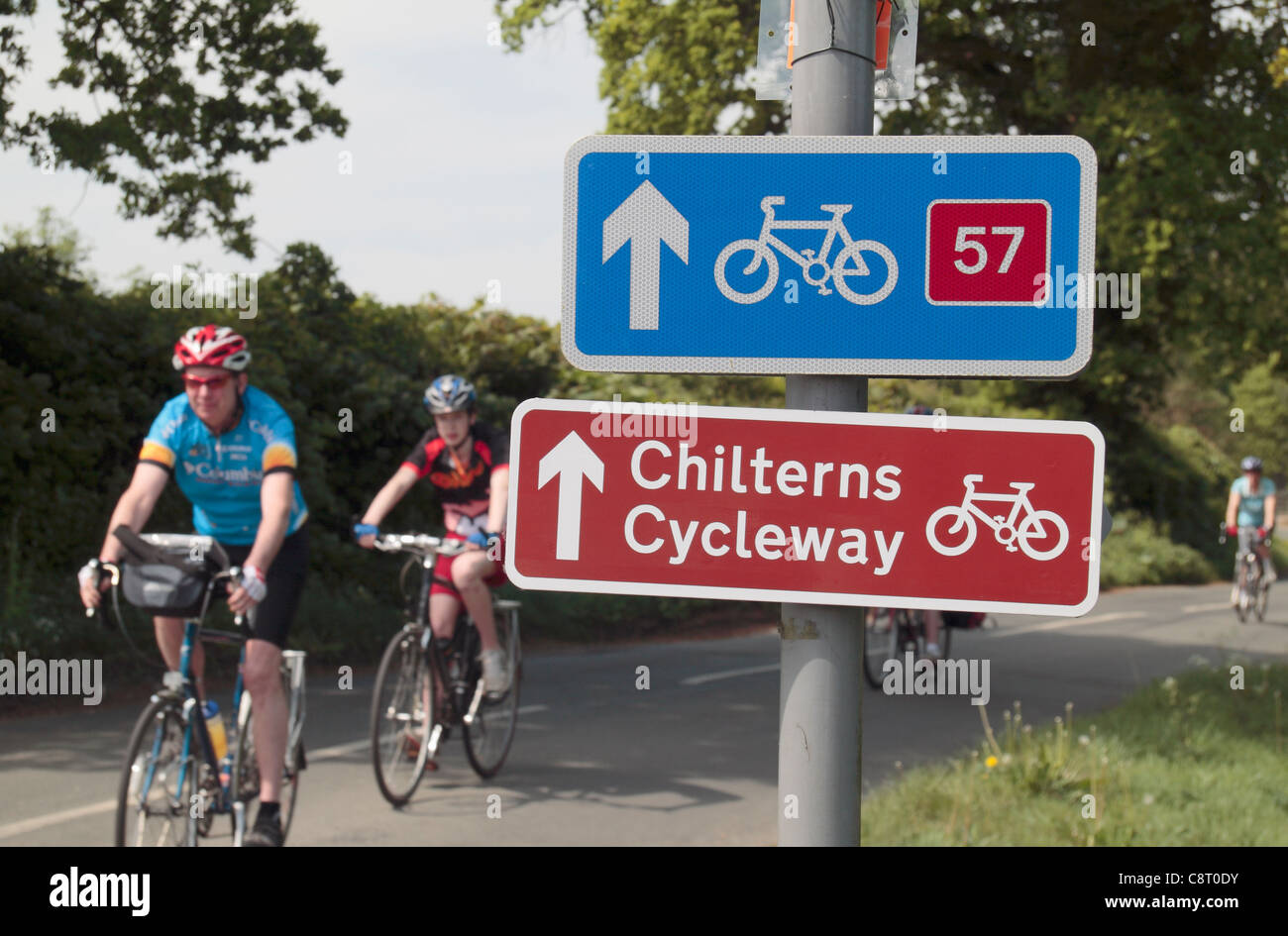 Cyclists ride past road signs for the Chilterns Cycleway and national cycle route 57 near Great Missenden, Buckinghamshire, UK. Stock Photo