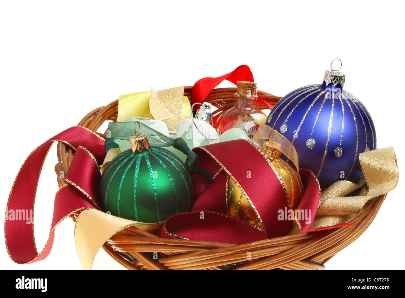 Christmas bauble decorations and ribbons in a basket against a white background Stock Photo