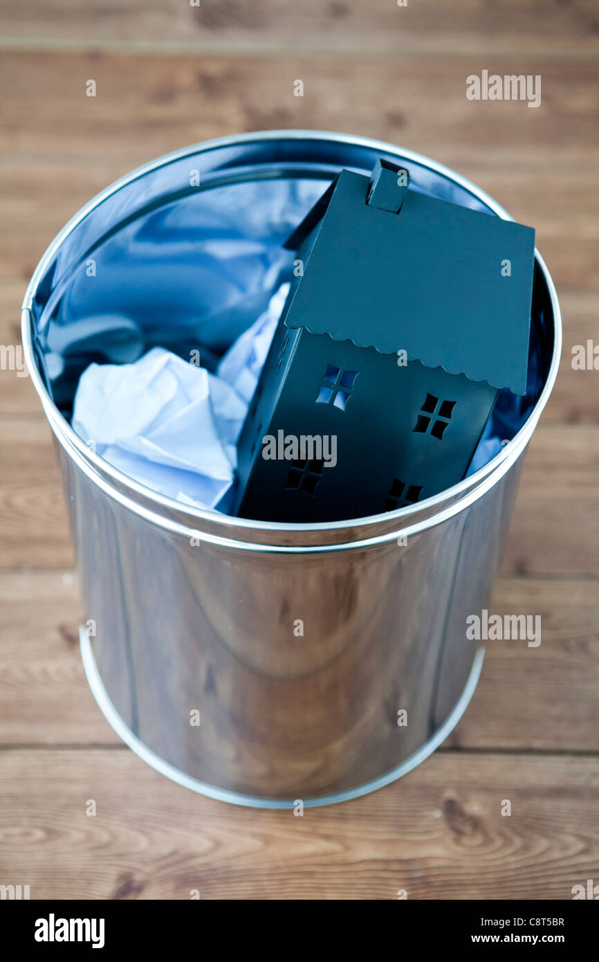 Architectural model of house and crumbled paper in garbage can Stock Photo