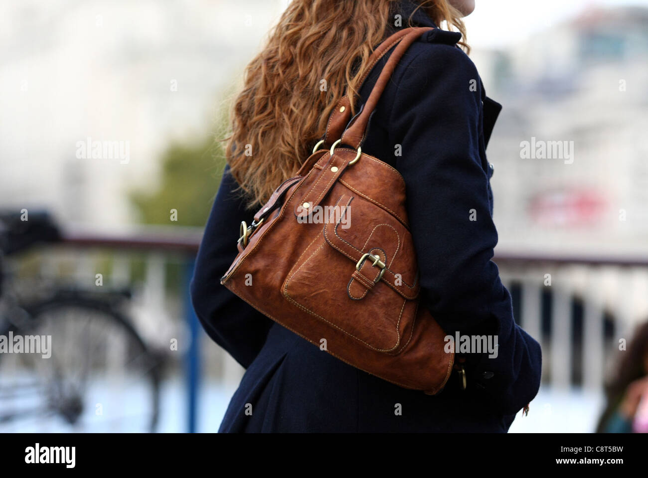 a female carrying a brown shoulder bag while walking in the street ...