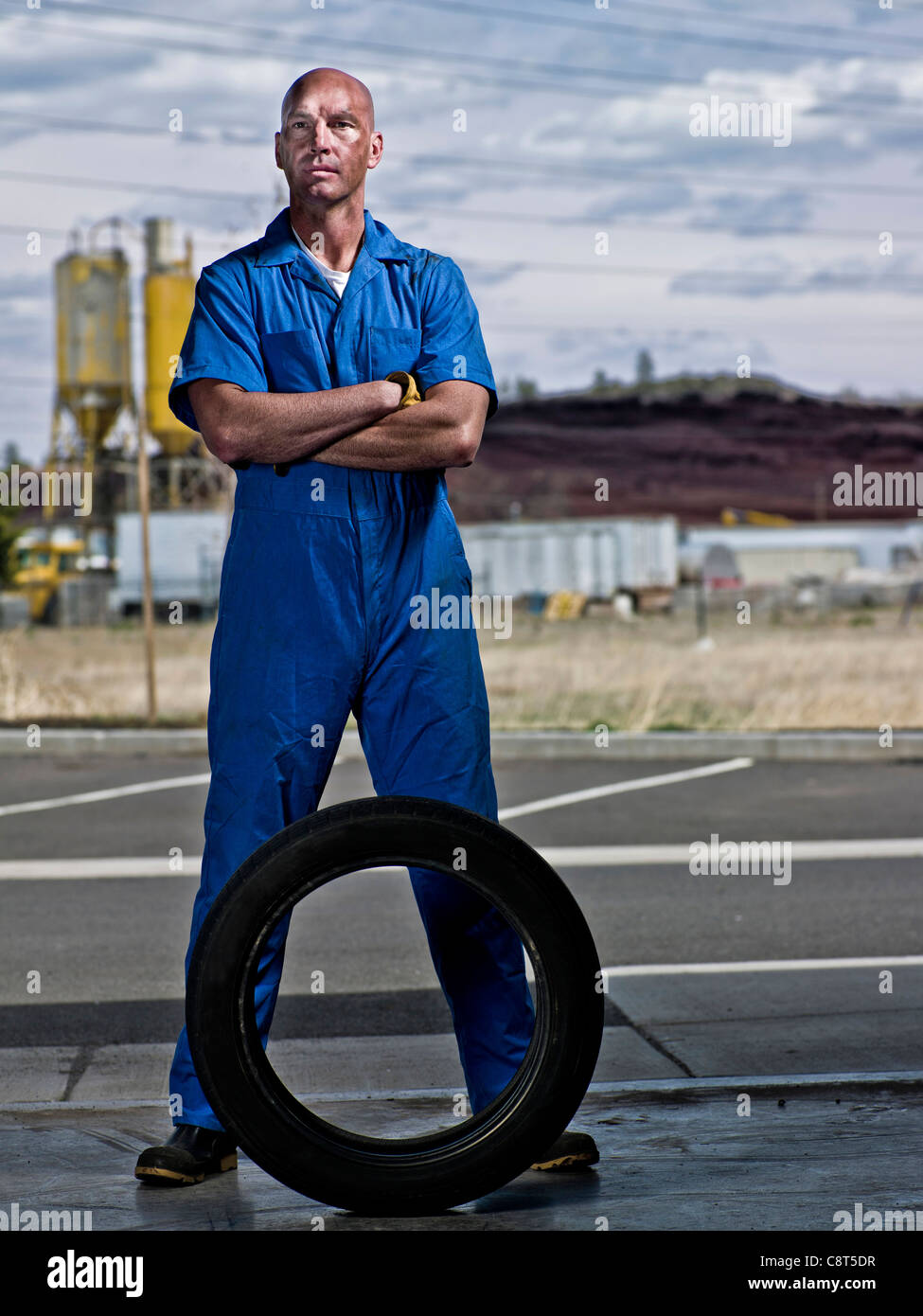 Serious mechanic standing with tire Stock Photo