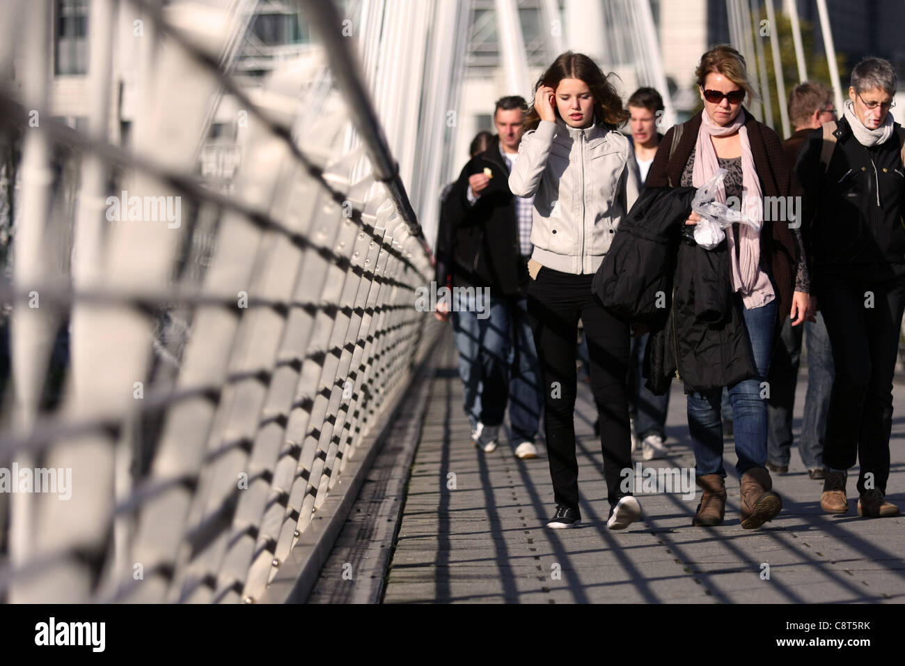 a low view along The Golden Jubilee Bridge, London, with people walking towards the camera Stock Photo