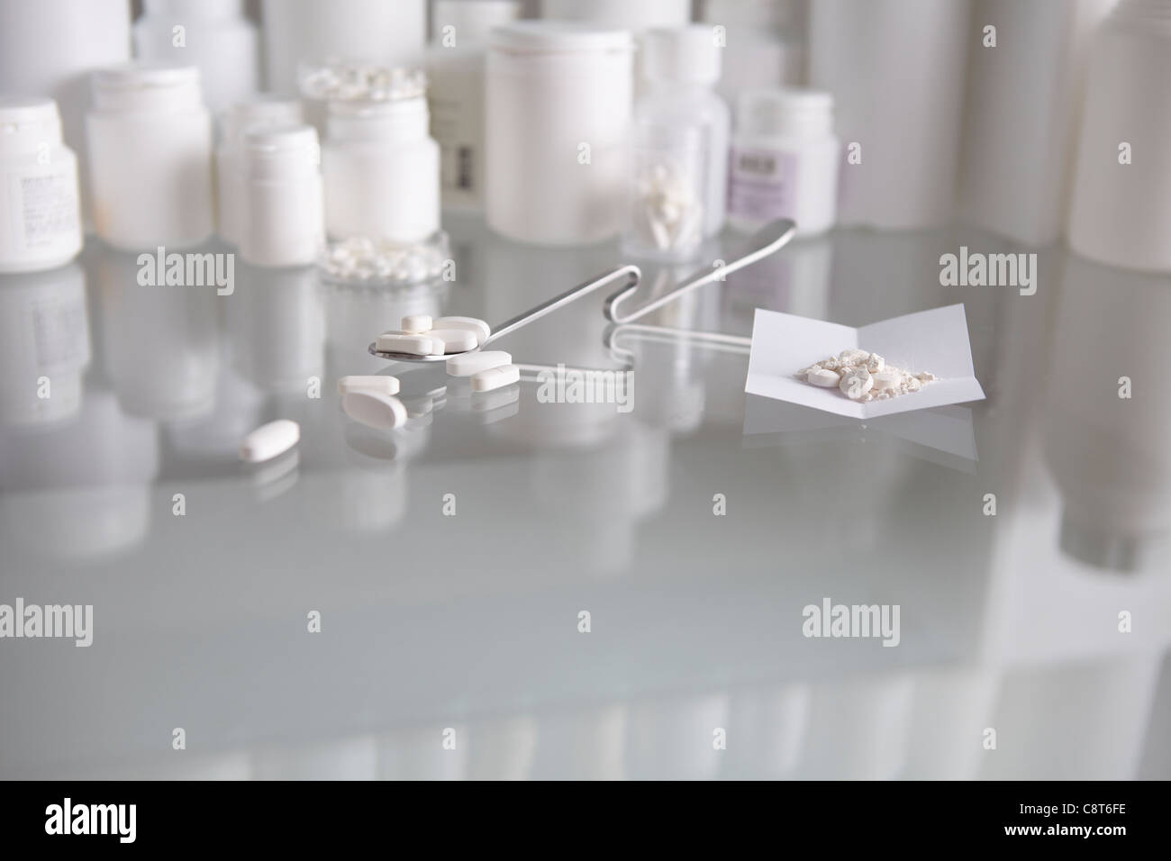 Pills on paper along with medical equipment kept on table with pill bottles in the background Stock Photo