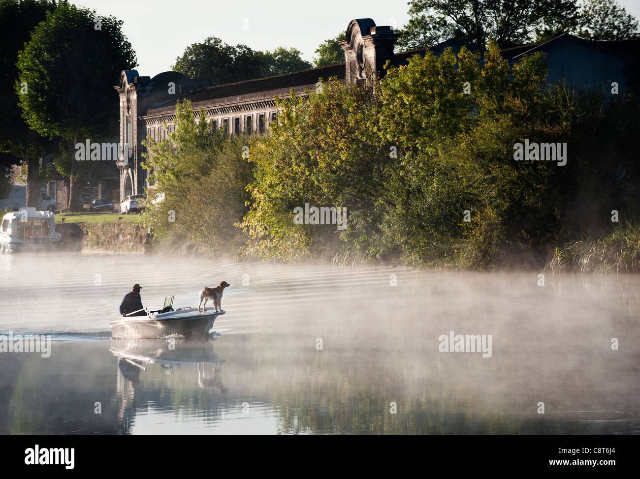 A man on a boat passes by the cognac house of Tiffon, on the banks of the Charente river, Jarnac, Charente departement, France Stock Photo