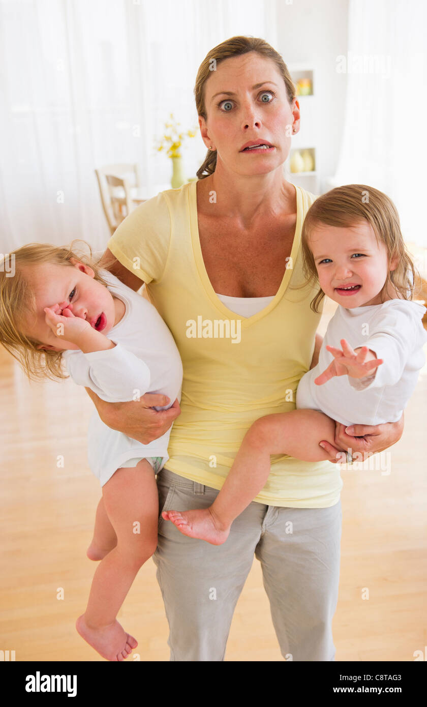 USA, New Jersey, Jersey City, Mother holding crying daughters and making facial expression Stock Photo
