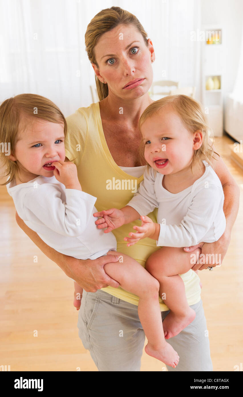 USA, New Jersey, Jersey City, Mother holding crying daughters and making facial expression Stock Photo