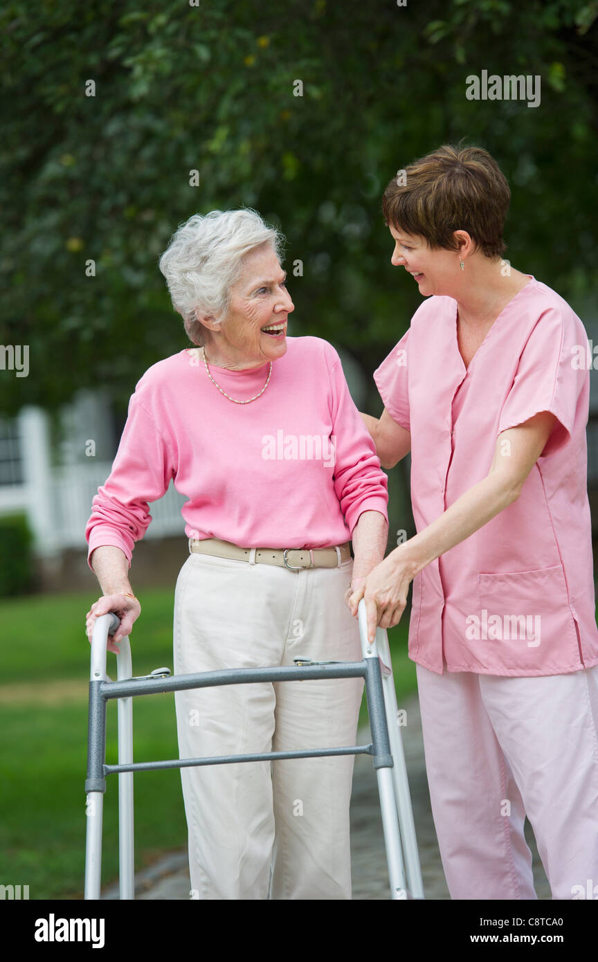 USA, New York State, Old Westbury, Senior woman walking with walker with help of nursing assistant Stock Photo