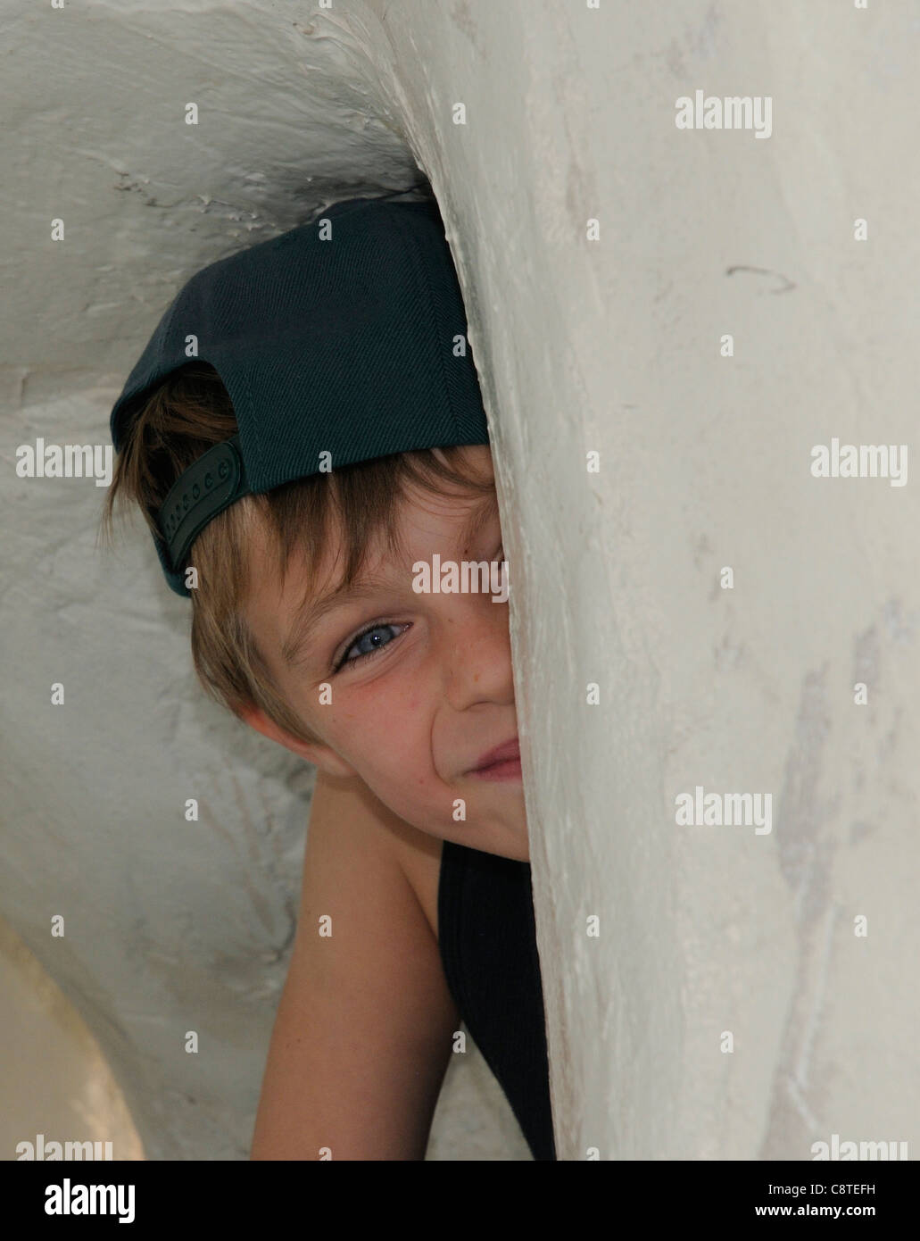 A smiling young boy peeping out from a hiding place Stock Photo