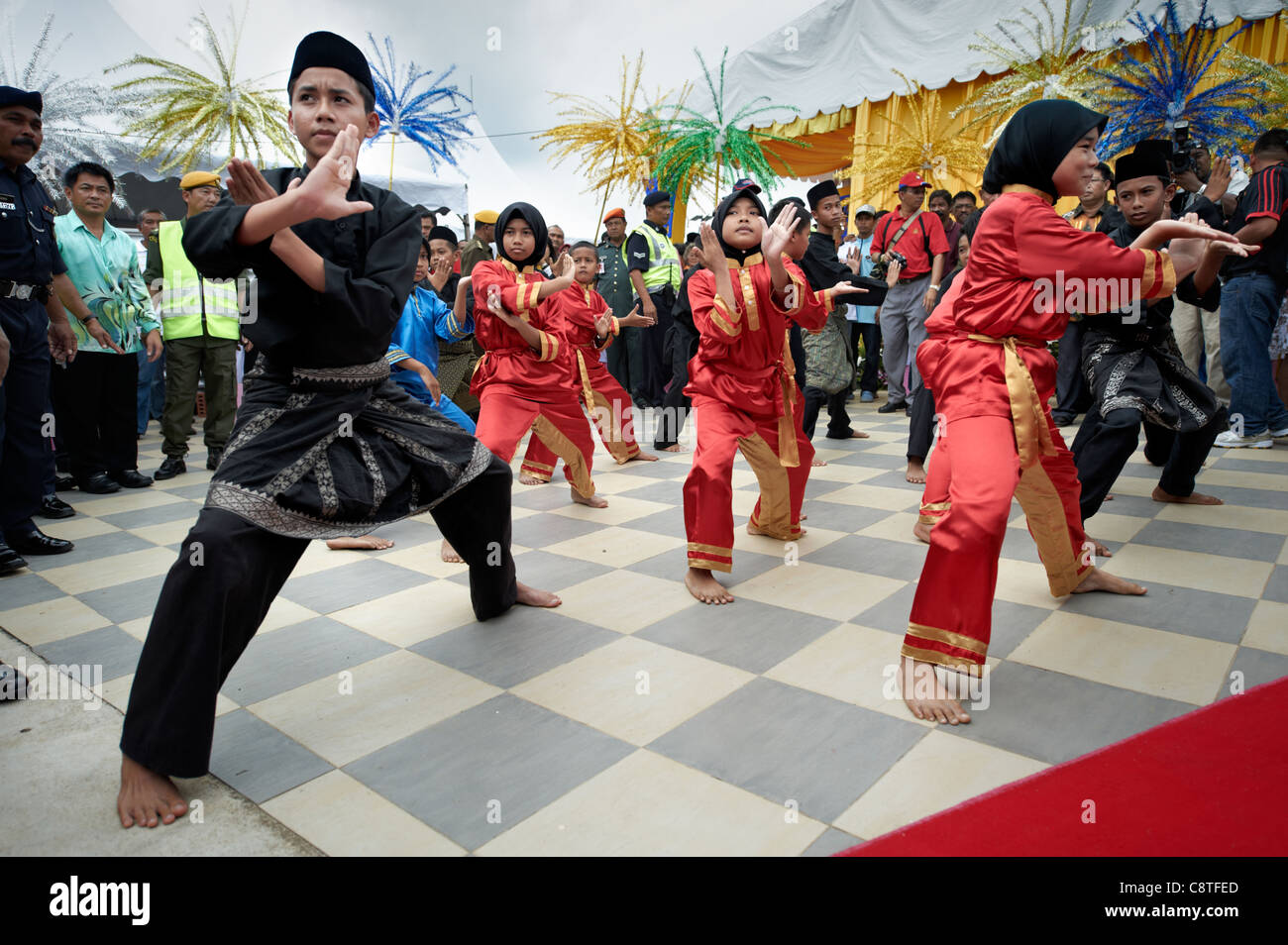 Young Malaysian children in traditional clothing performing for a crowd