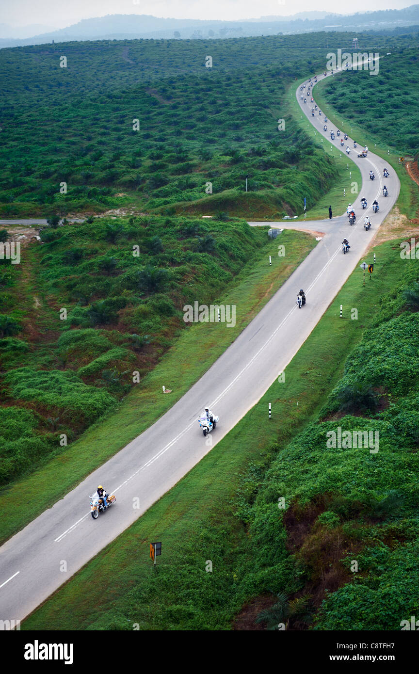Motorcycles driving down a highway in Johor, through forest greenery. Stock Photo