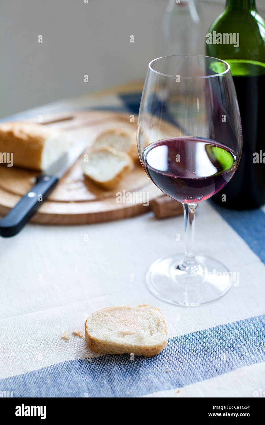 Close-up of slice of cinnamon bun and red wine glass with wine bottle in background Stock Photo