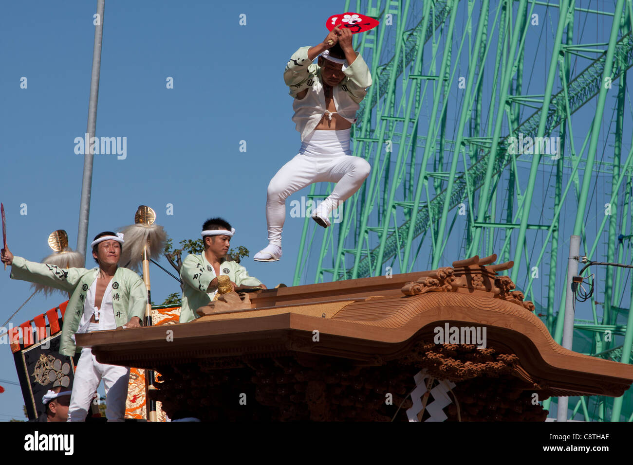 A man, called a daiku kata, jumps across the roof of a Danjiri float as it turns a corner during he Kishiwada danjiri matsuri, Osaka, Japan Stock Photo