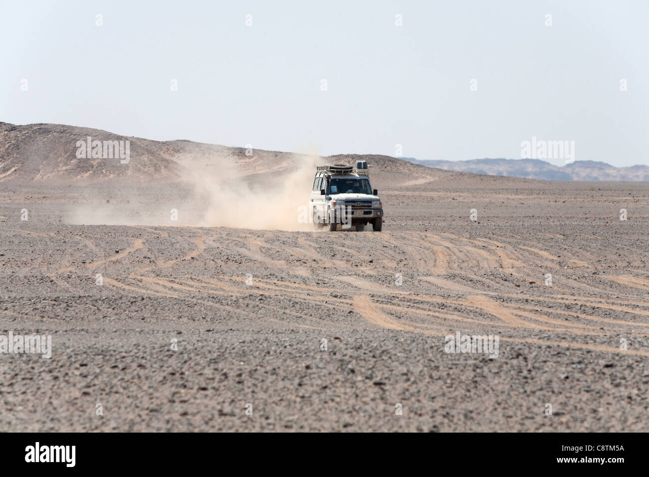 Long shot of four wheel drive vehicle approaching camera kicking up dust trails in Egypt's Eastern desert Stock Photo