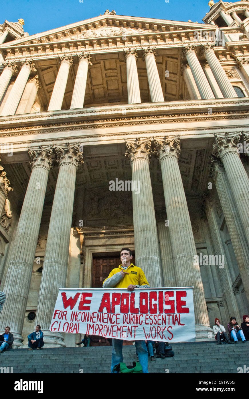 Protester with poster in front of the St Pauls portico,'We apologise for inconvenience during essential global improvement work' Stock Photo