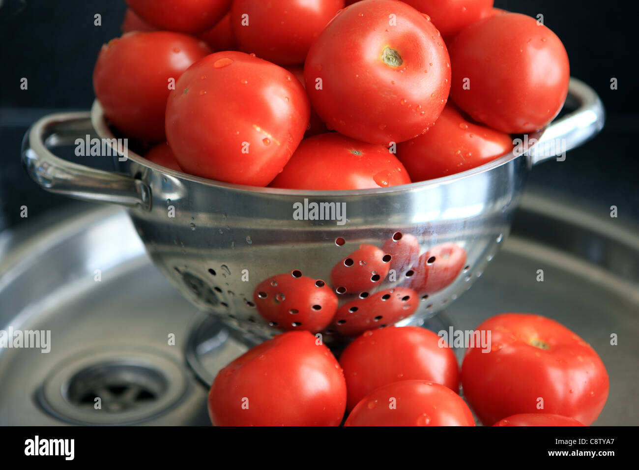 Tomatoes in stainless steel colander and on stainless steel sink Stock Photo