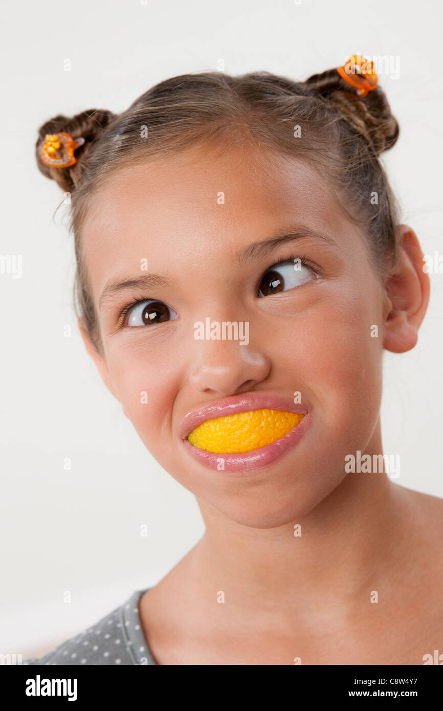 studio-portrait-of-girl-with-slice-of-lemon-in-mouth-C8W4Y7.jpg