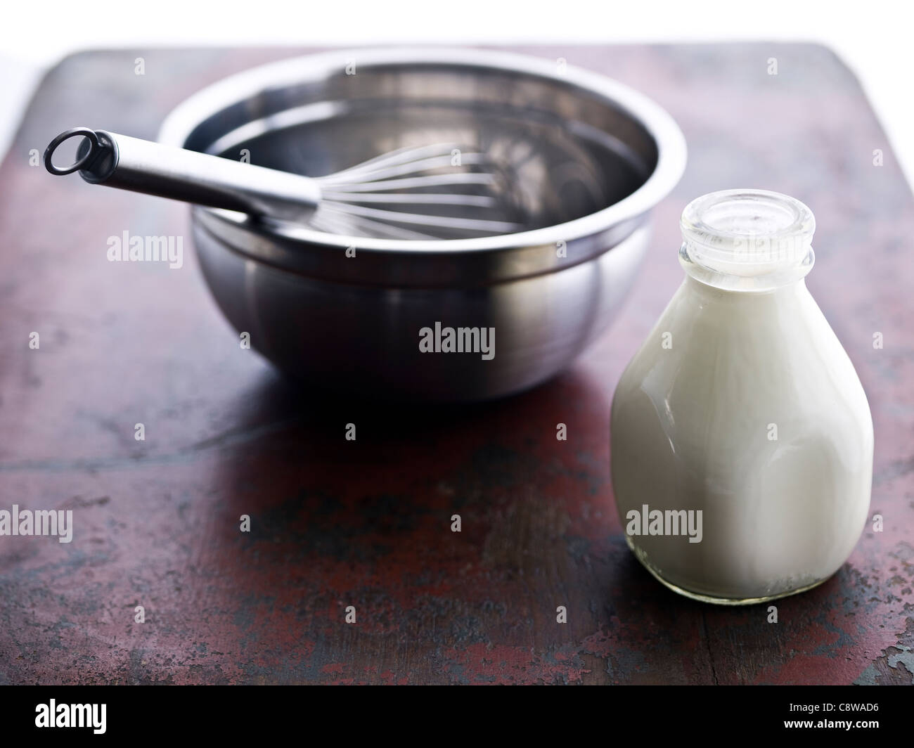 Bowl, wire whisk and milk in bottle Stock Photo