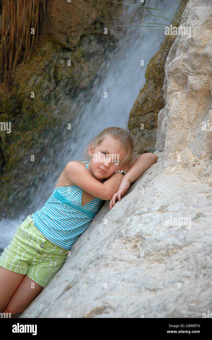 child girl on the background of a waterfall poses Stock Photo