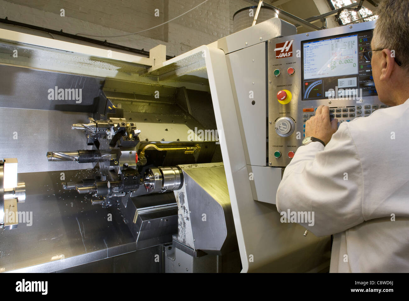 Engineer programs data onto a CNC lathe machine loaded with tools prior to machining Stock Photo