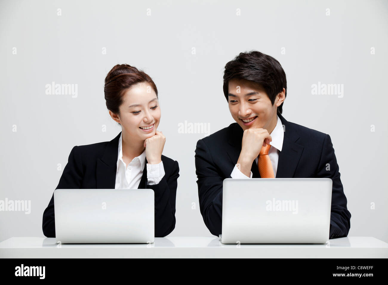 Asian Businessman And Businesswoman  Peeking At Other Laptop Stock Photo