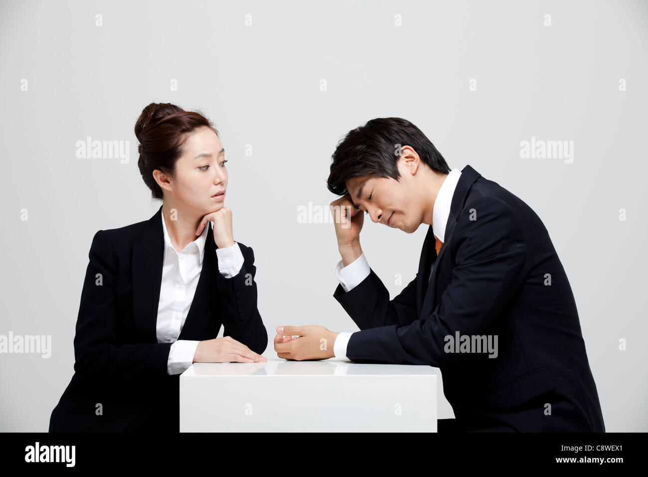Asian Businesswoman Looking At Depressed Businessman Stock Photo