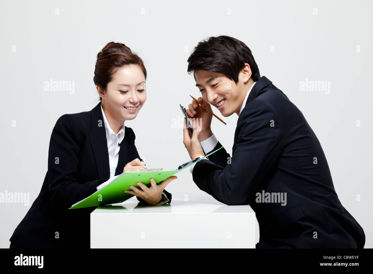 Asian Businessman And Businesswoman Working At Desk Facing Each Other Stock Photo