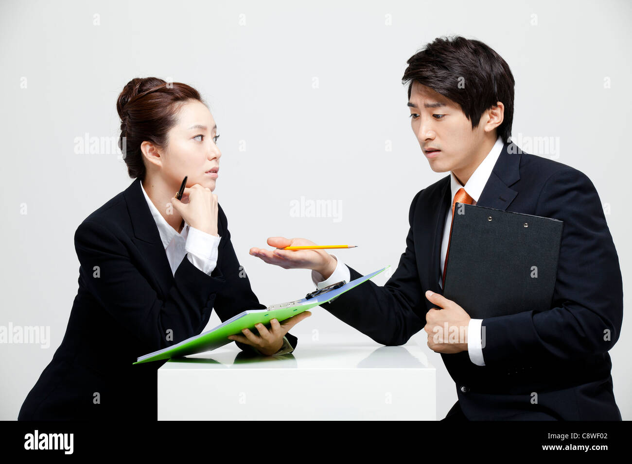 Asian Businessman And Businesswoman Working At Desk Facing Each Other Stock Photo