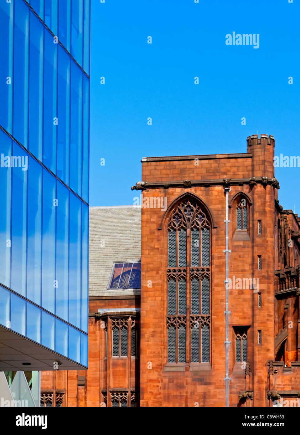 Modern glass tower block next to old red brick building in central Manchester England UK Stock