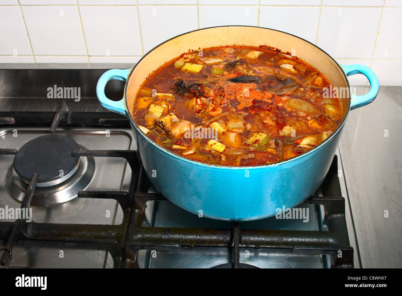 Stock simmering gently in a pot on a gas stove Stock Photo
