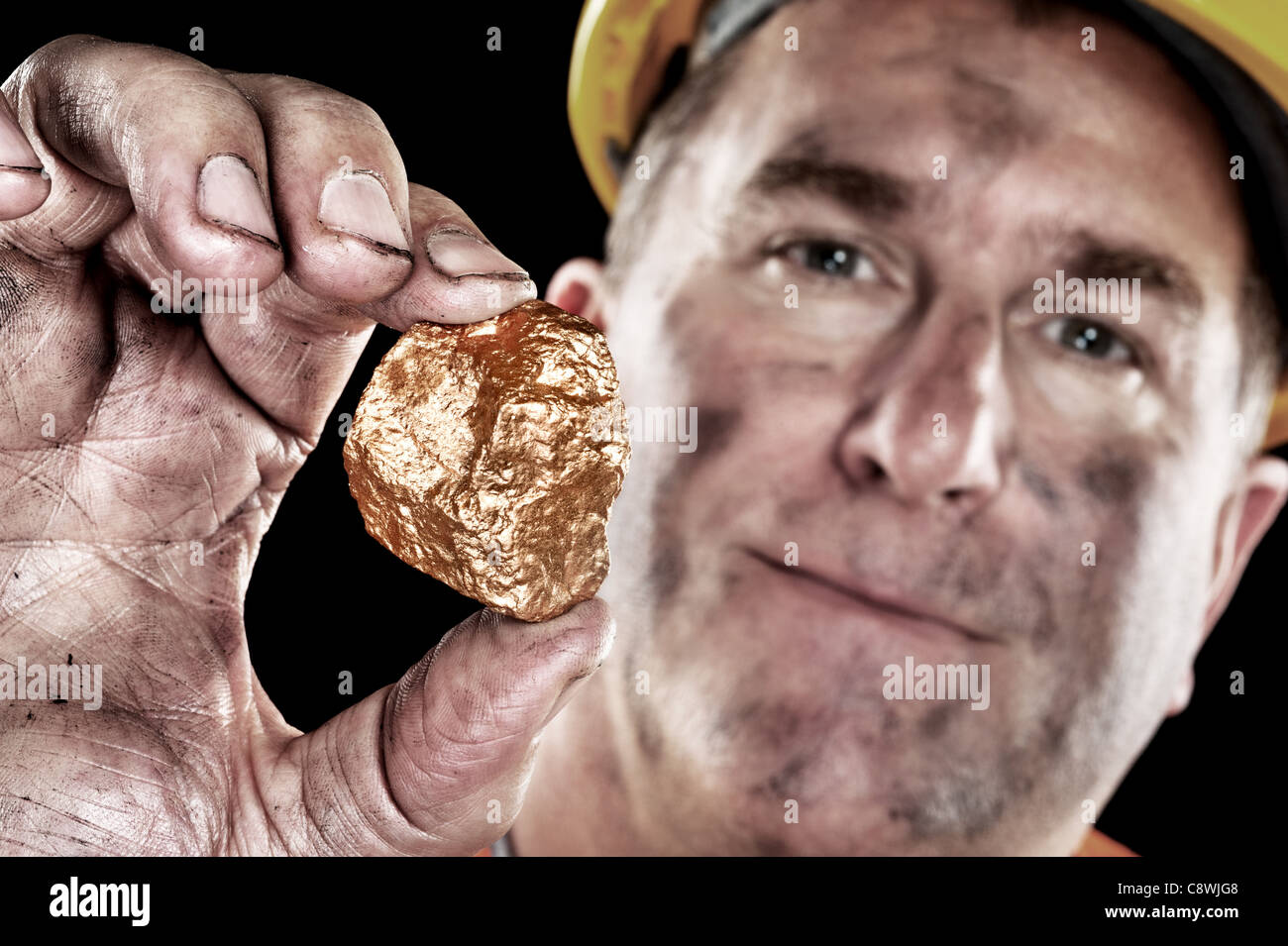 A gold miner shows a golden nugget freshly excavated from a mine. Stock Photo