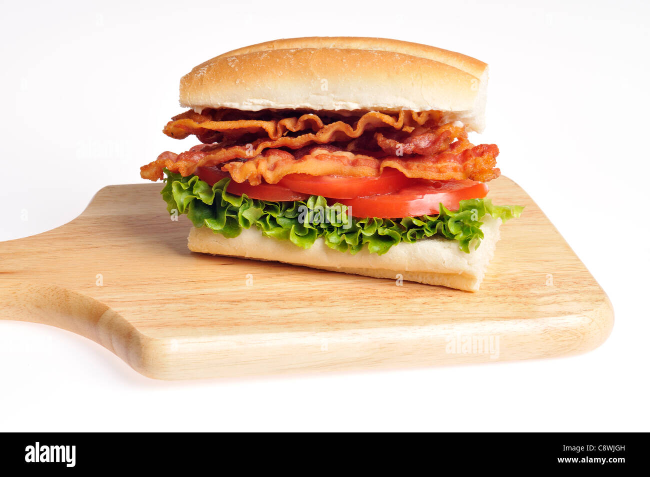 Bacon, Lettuce and Tomato BLT sandwich on a  bread roll on a wood cutting board on a white background. USA Stock Photo