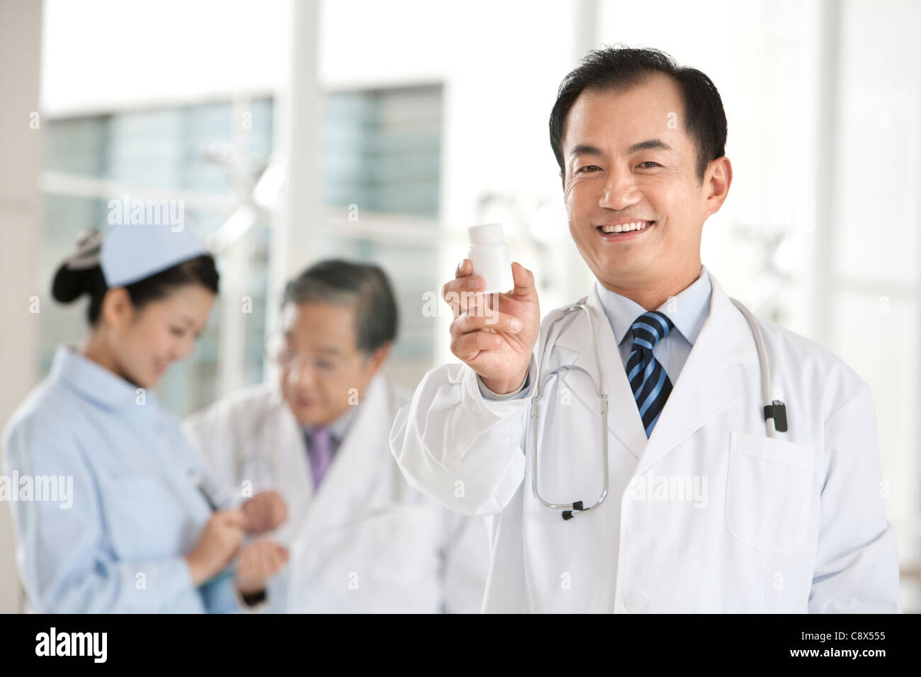 Doctor Offers Perscription Medicine, Doctor and Nurse in Background Stock Photo