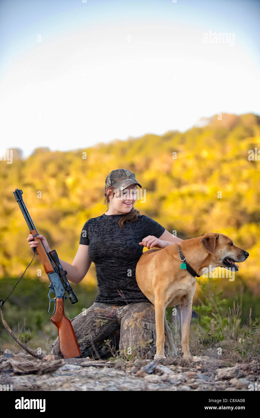 Attractive woman in camouflage outfit with gun and dog Stock Photo