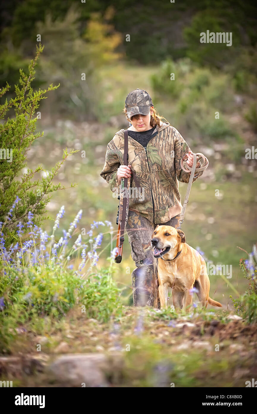 Hunting season - Female hunter with dog walking through woods Stock Photo