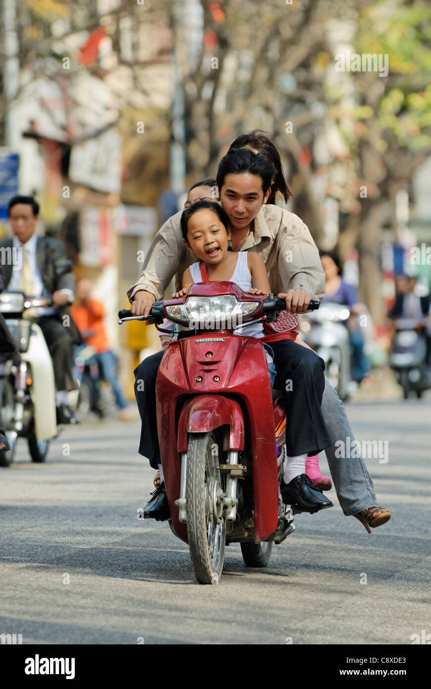 Asia, Vietnam, Hanoi. Hanoi old quarter. Vietnamese family riding on a small motorbike through Hanoi.... Stock Photo