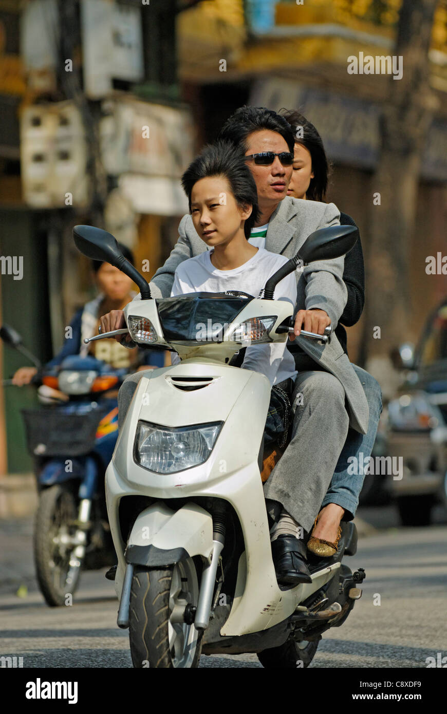 Asia, Vietnam, Hanoi. Hanoi old quarter. Vietnamese family riding on motorbike through Hanoi.... Stock Photo