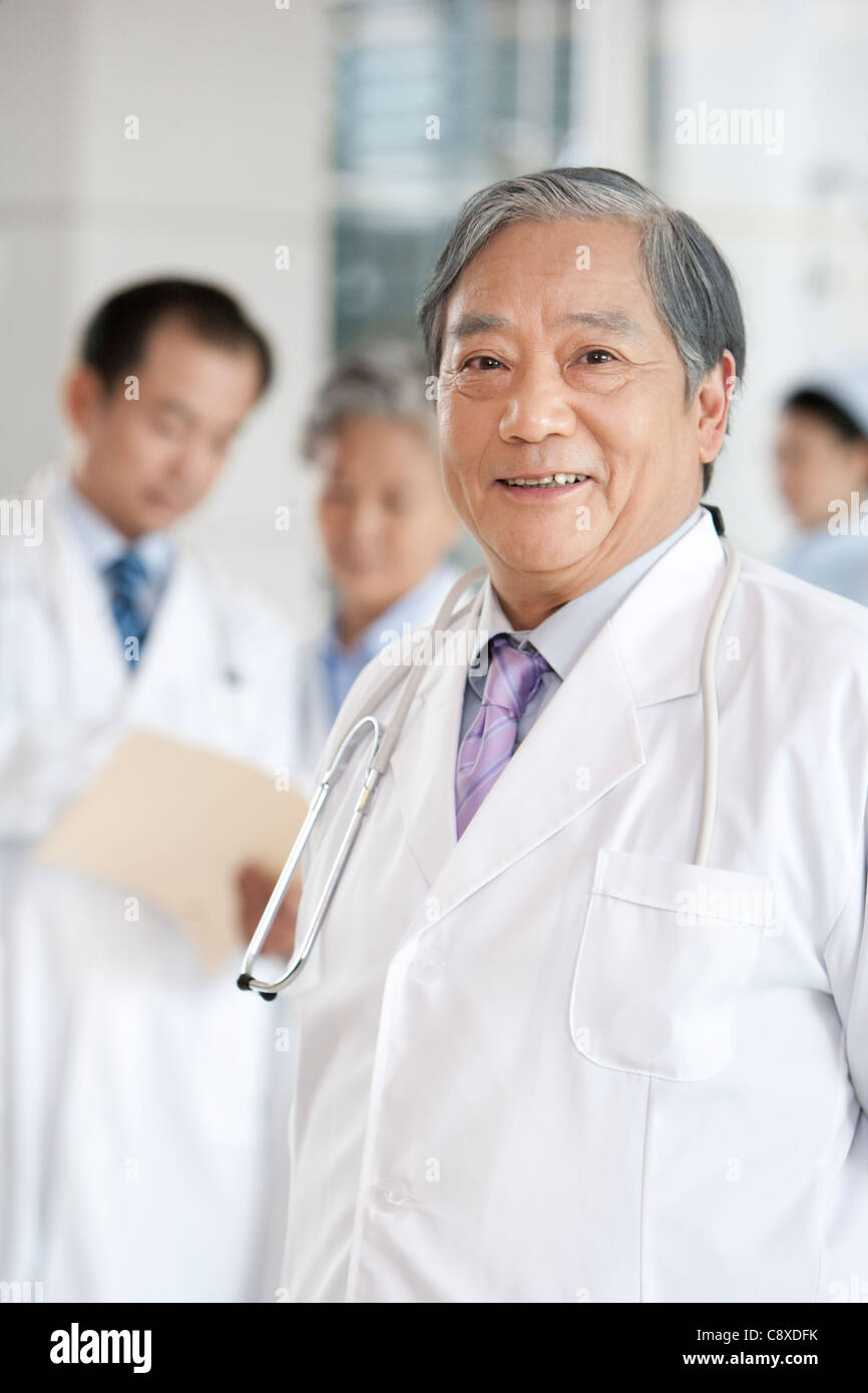 Senior Doctor with Doctors and Nurse in Background Stock Photo - Alamy