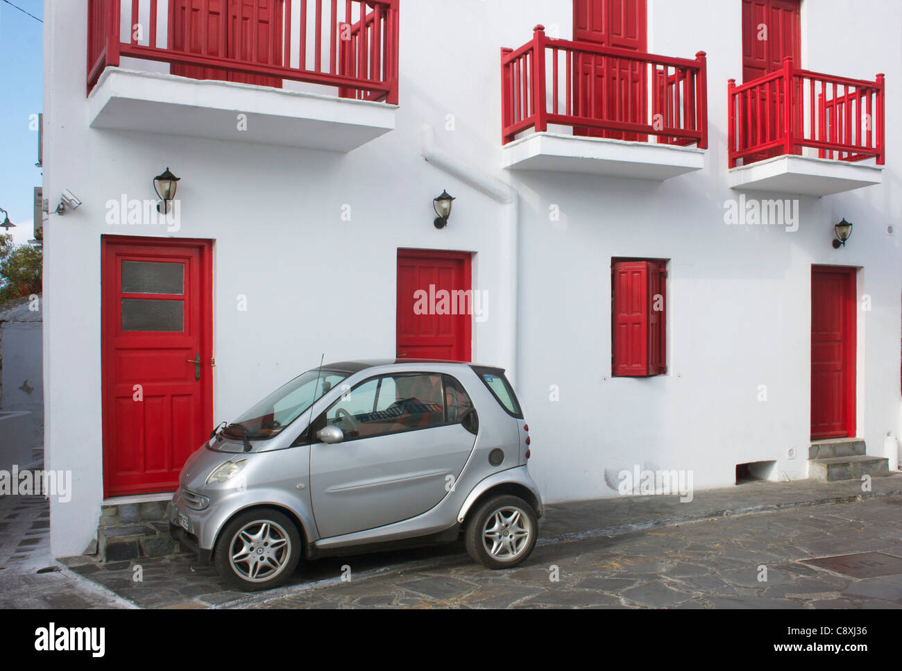 Mini car parked in front of a red & white residence on the Greek island of Mykonos. Stock Photo