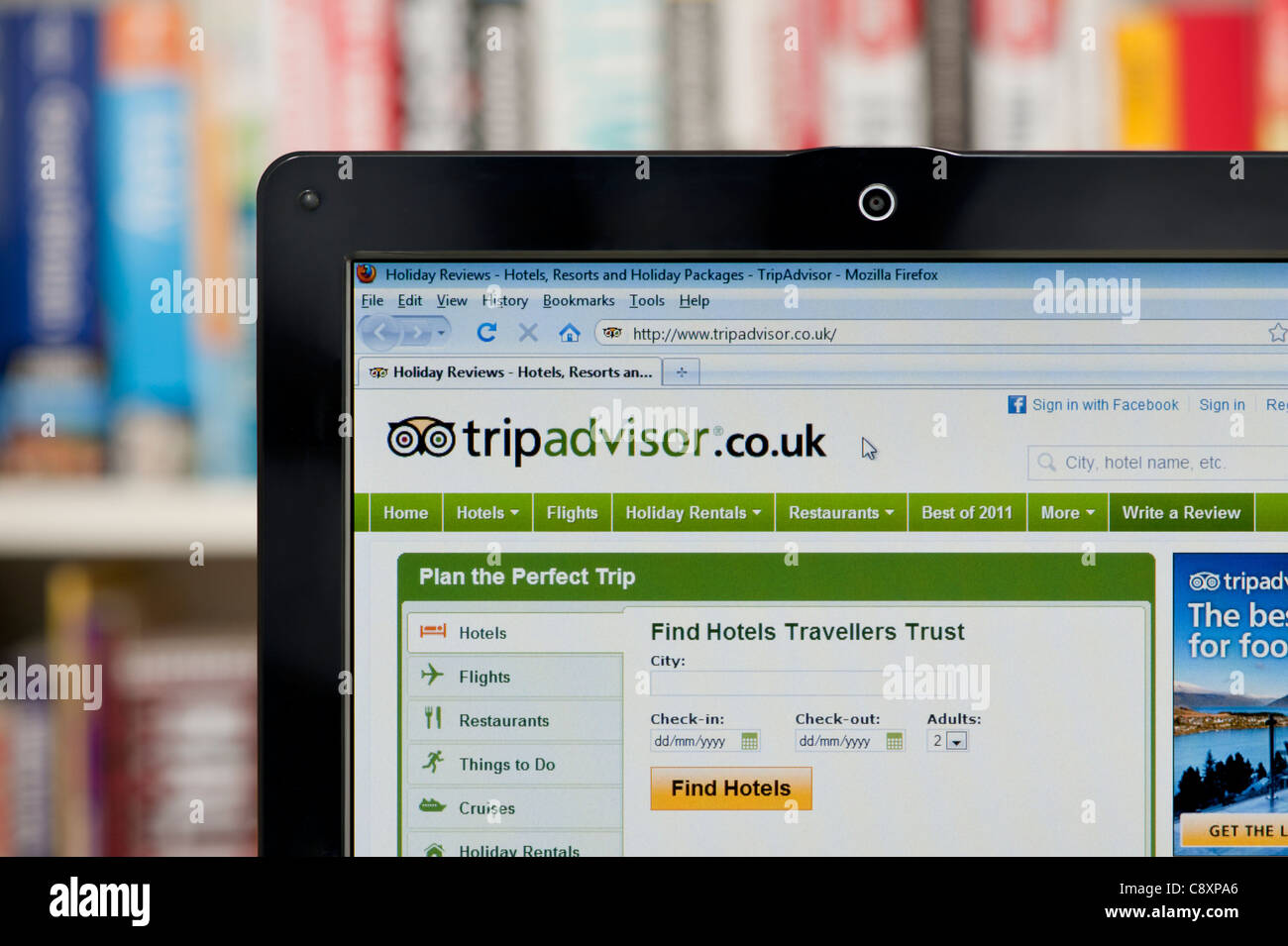 The Trip Advisor website shot against a bookcase background (Editorial use only: print, TV, e-book and editorial website). Stock Photo