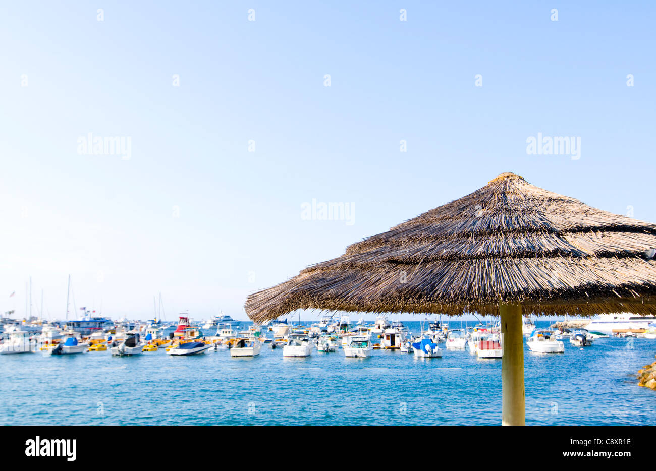 Tiki-Style Palapa against background of Bay and Anchored Yachts Stock Photo