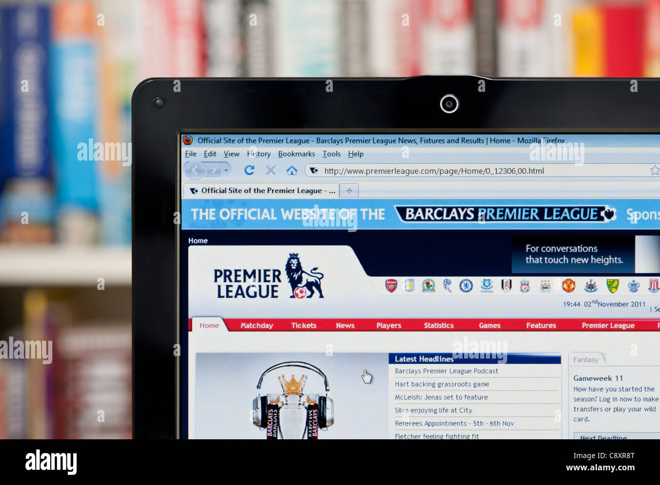 The Premier League website shot against a bookcase background (Editorial use only: print, TV, e-book and editorial website). Stock Photo