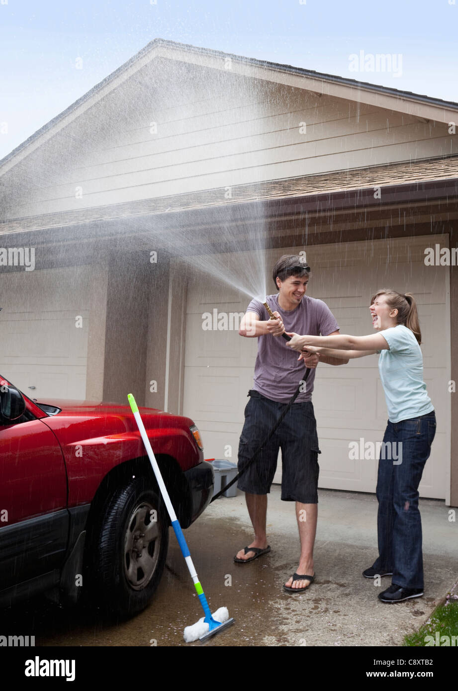 USA, Oregon, Ashland, young couple washing car in front of garage Stock