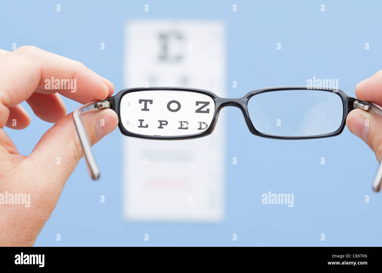 Hands holding glasses in front of eye chart, studio shot Stock Photo Alamy