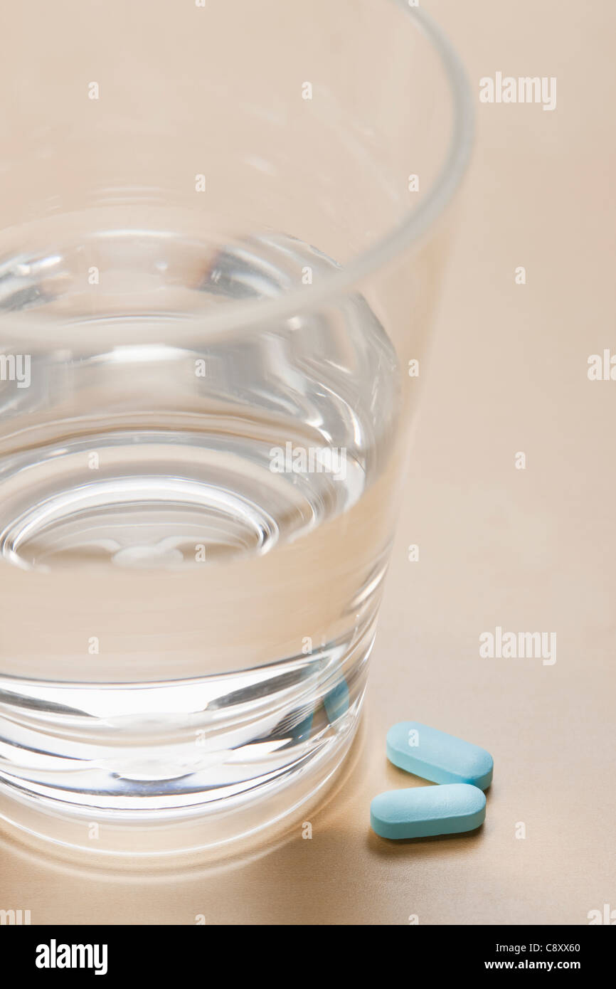 Pills near glass with water, studio shot Stock Photo